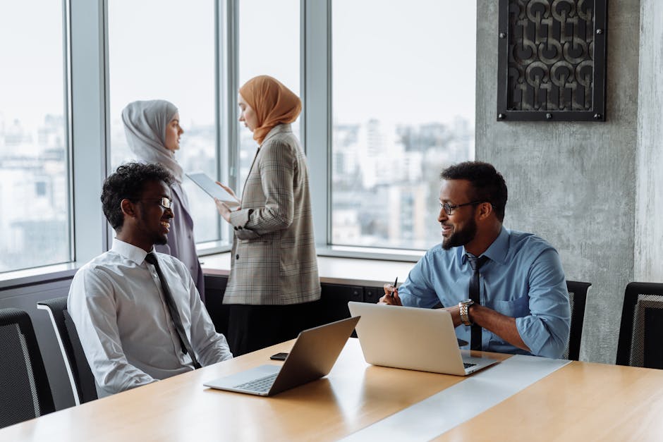 A diverse group of colleagues collaborating in a modern office with laptops and documents.